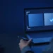 Illustration: a reviewer seen from behind, holding a pen at a laptop that shows two answer panels with a tick on one, for what an AI trainer does