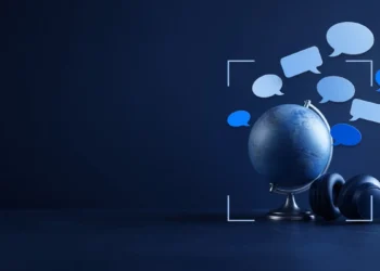 Illustration: a desk globe and headphones under floating blank speech bubbles in blue, for multilingual AI training jobs