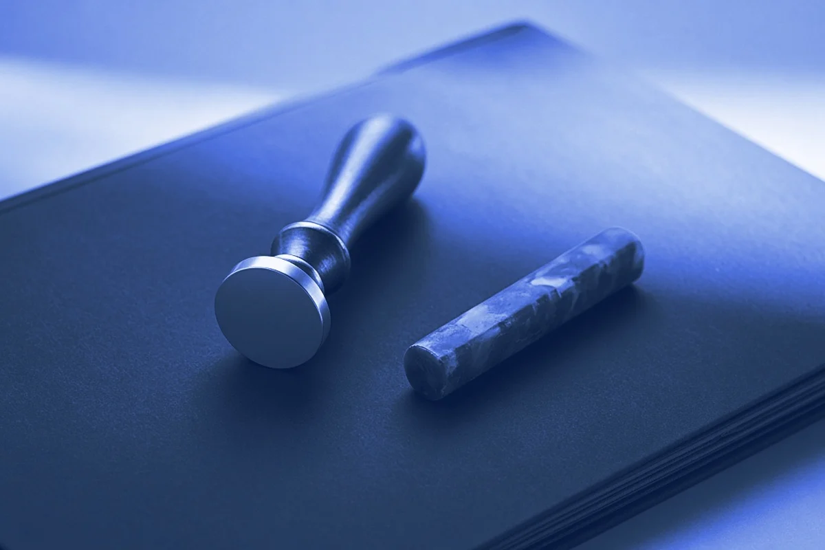 A brass wax seal stamp and a stick of sealing wax on a closed folder, for legal AI trainer jobs