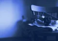 A chest camera strap beside a folded apron on a kitchen chair, for robotics data collection jobs