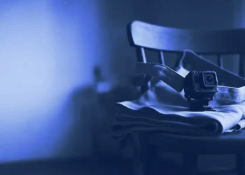A chest camera strap beside a folded apron on a kitchen chair, for robotics data collection jobs